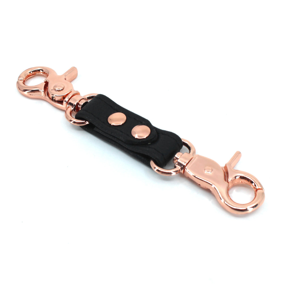 https://www.restrainedgrace.com/cdn/shop/products/restrained-grace-bondage-strap-the-leather-double-snap-hook-in-black-rose-gold-22738246795463.jpg?v=1685656774&width=1090